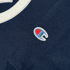 Detailed close-up navy Hieroglyphics logo on the chest and Champion logo on the sleeve.