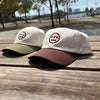 Photo image (left to right) of cream with olive logo and cream with brown dad hats with contrasting brims and embroidered logo
