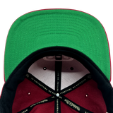 Detailed close up of cardinal red Hiero x Mitchell & Ness hat with green under visor and Mitchell & Ness taping inside crown.